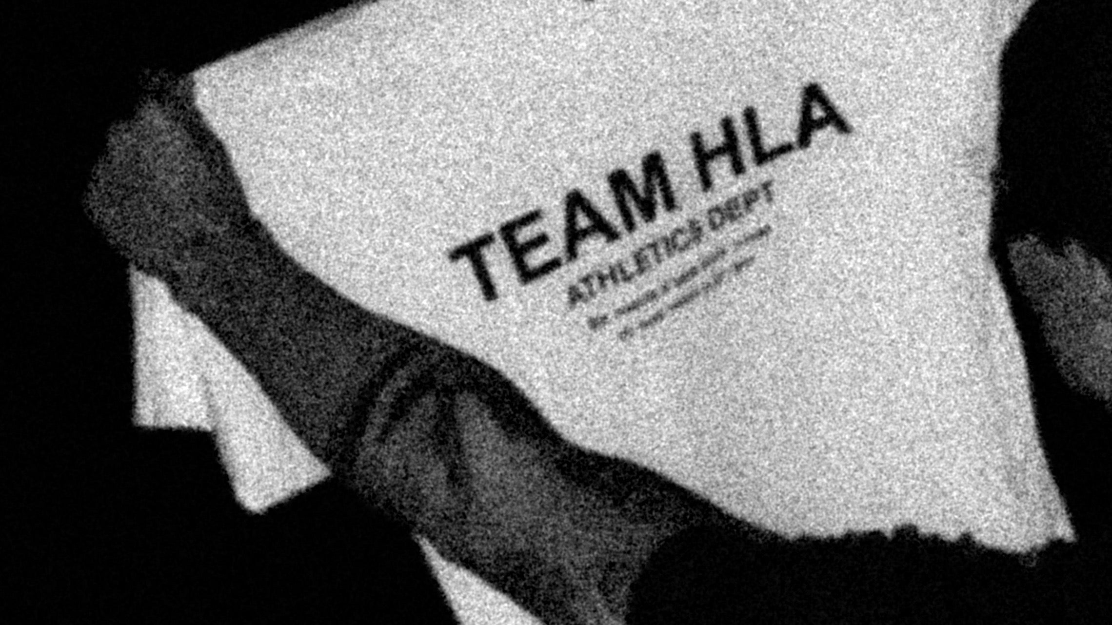 Holder opp hvit TEAM HLA-t-skjorte i moerket, 16:9